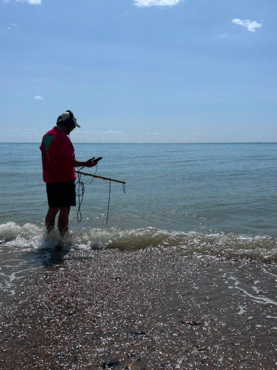 A participant standing in shallow water with recording equipment.